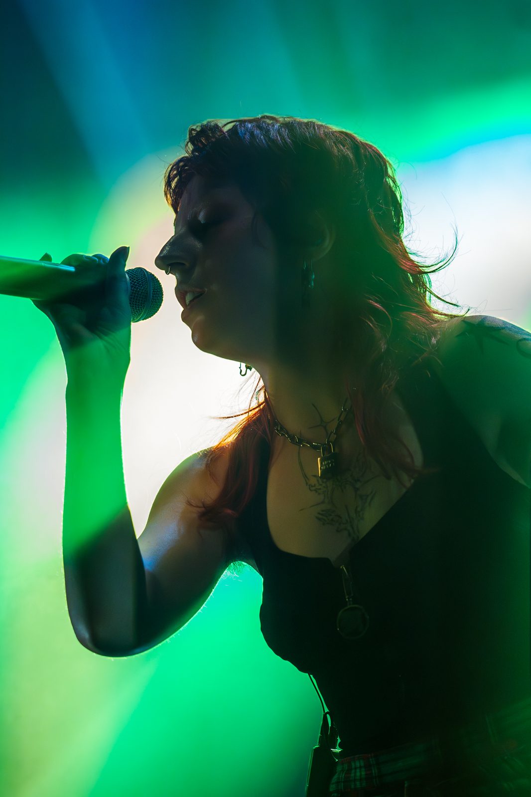 Gros plan sur une chanteuse au micro, silhouette verte