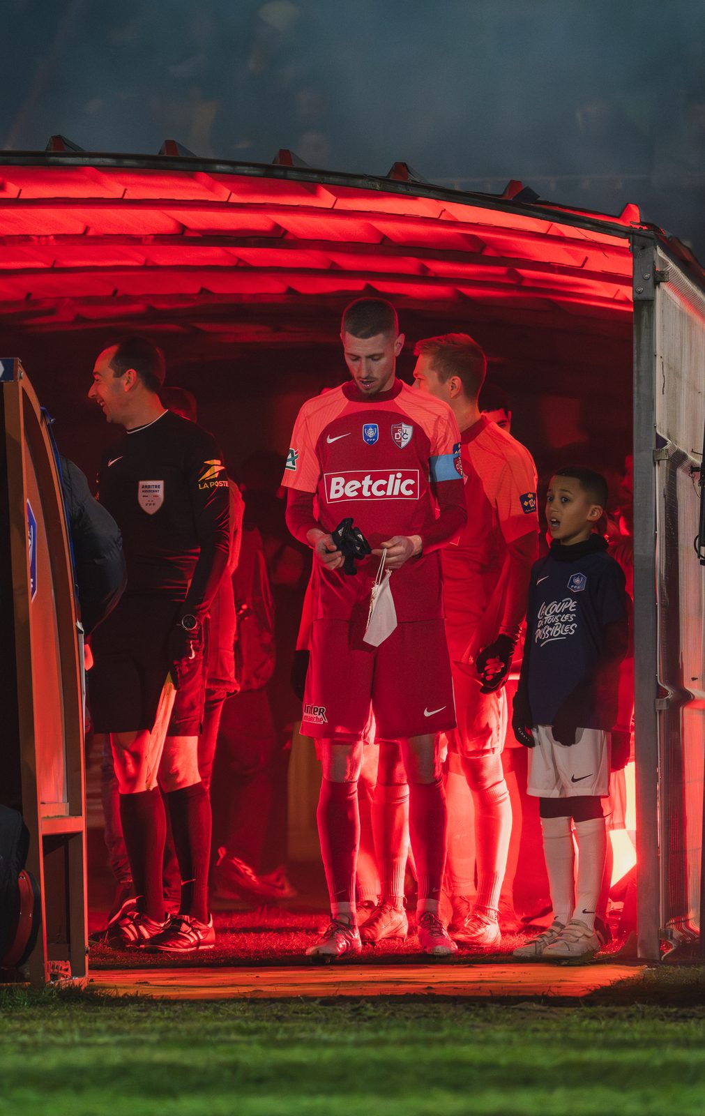 Joueurs à l'entrée du terrain, lumière rouge du tunnel